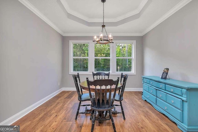 dining space with wood finished floors, baseboards, a tray ceiling, and a notable chandelier