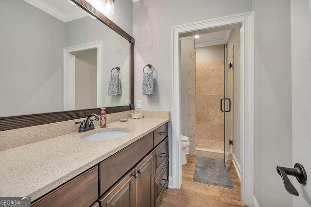 bathroom featuring wood finished floors, a shower stall, ornamental molding, toilet, and vanity