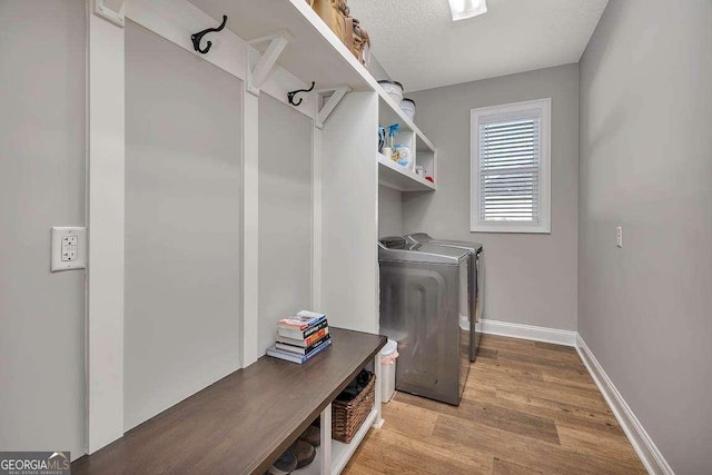 washroom featuring baseboards, laundry area, light wood-style flooring, and independent washer and dryer