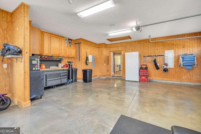 garage with a workshop area, wood walls, a garage door opener, and baseboards