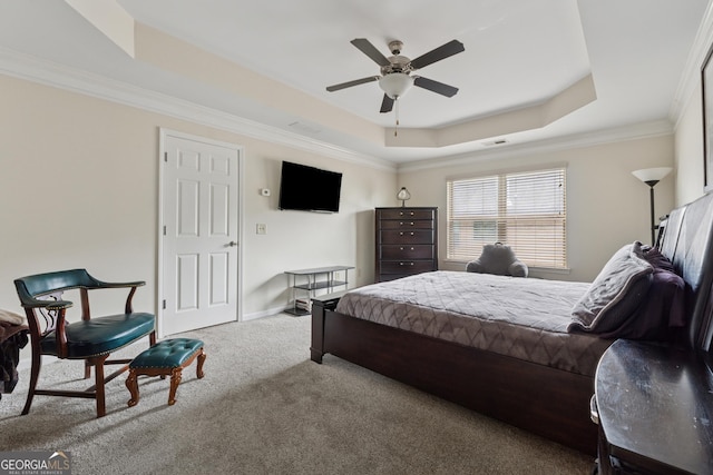 carpeted bedroom featuring ornamental molding, baseboards, visible vents, a ceiling fan, and a tray ceiling