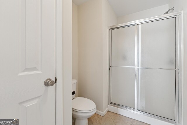 full bathroom featuring baseboards, a shower stall, toilet, and tile patterned flooring