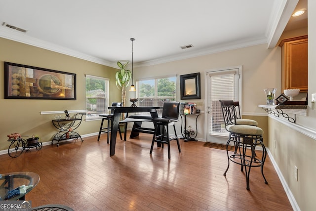 dining room with visible vents, crown molding, baseboards, and wood-type flooring