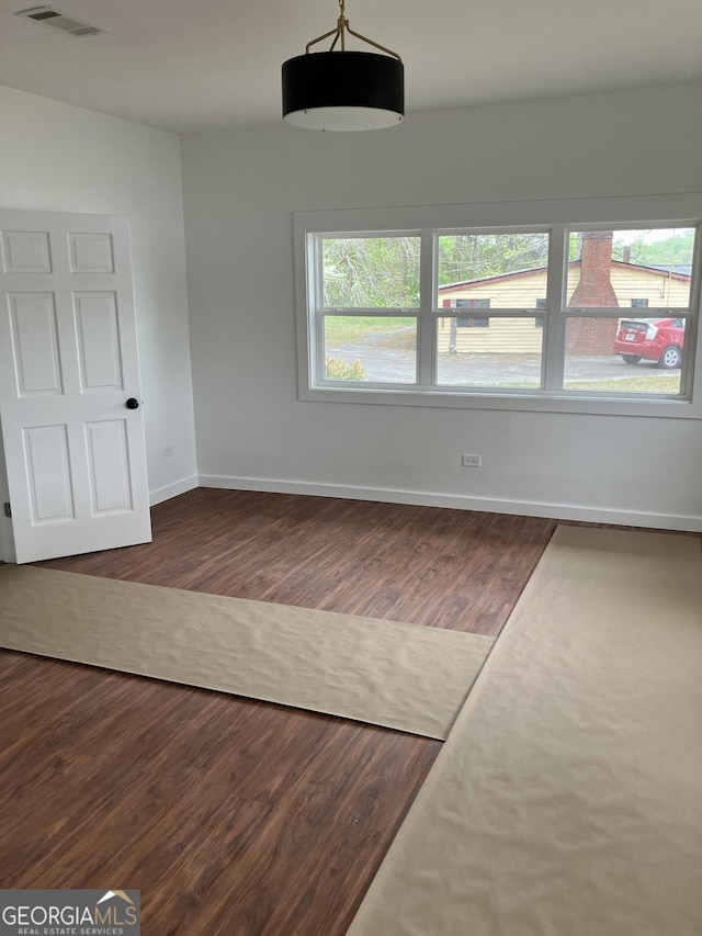unfurnished dining area with visible vents, dark wood-style flooring, and baseboards