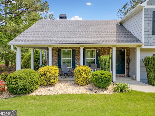 exterior space featuring a porch, a shingled roof, a chimney, a front lawn, and stone siding