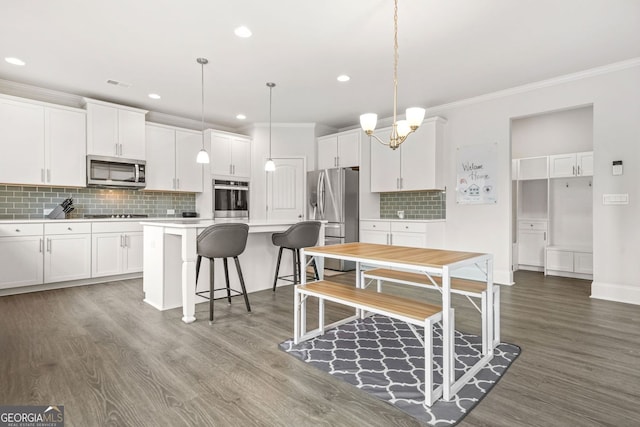 1606 Chancery Ln, Lithia Springs, GA 30122 - kitchen featuring appliances with stainless steel finishes, wood finished floors, light countertops, white cabinetry, and ornamental molding