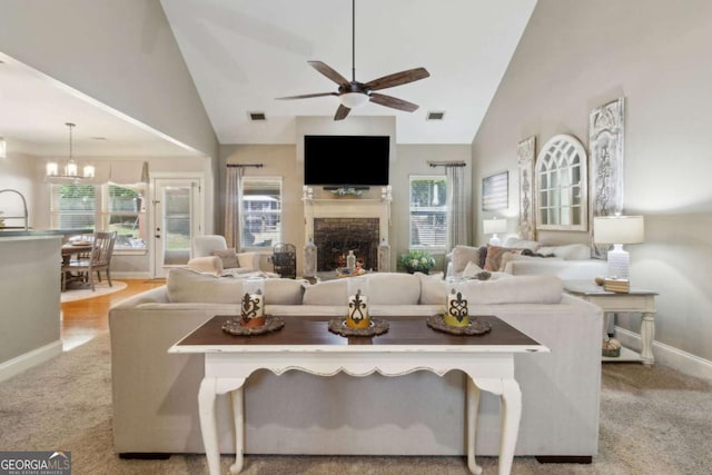 living room with a fireplace, plenty of natural light, ceiling fan with notable chandelier, and baseboards