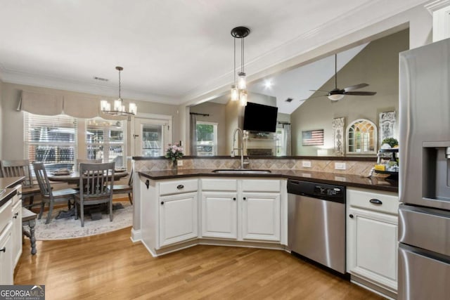 kitchen featuring a sink, light wood-type flooring, dark countertops, white cabinets, and appliances with stainless steel finishes