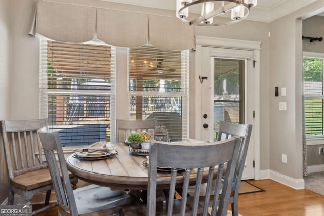 dining space featuring baseboards, wood finished floors, a chandelier, and crown molding