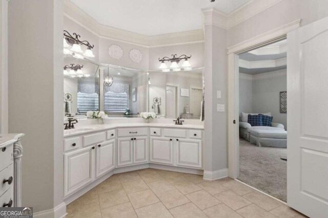 bathroom with tile patterned floors, ornamental molding, double vanity, and a sink