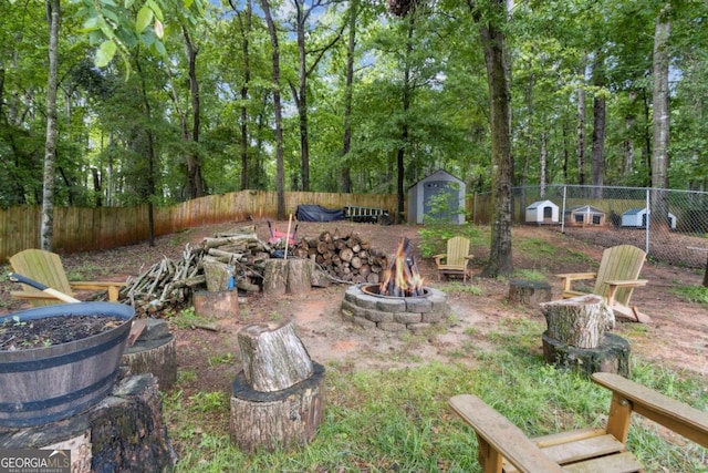 view of yard featuring an outdoor structure, a fire pit, a storage shed, and a fenced backyard