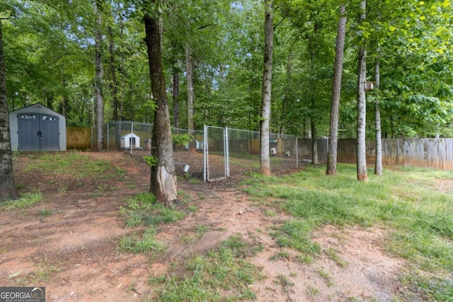 view of yard featuring fence, a gate, a shed, and an outbuilding