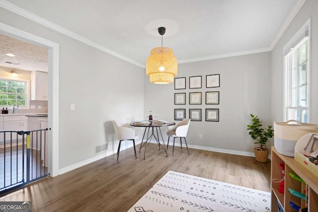 dining room with visible vents, baseboards, crown molding, and wood finished floors