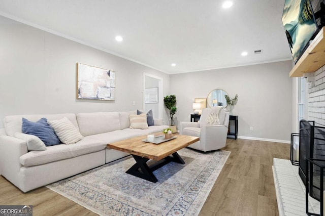living room with recessed lighting, ornamental molding, wood finished floors, and a fireplace