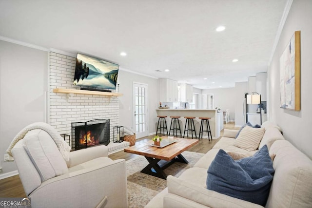living room featuring recessed lighting, ornamental molding, baseboards, and a brick fireplace