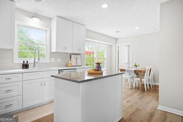kitchen featuring a sink, tasteful backsplash, a textured ceiling, and white cabinetry
