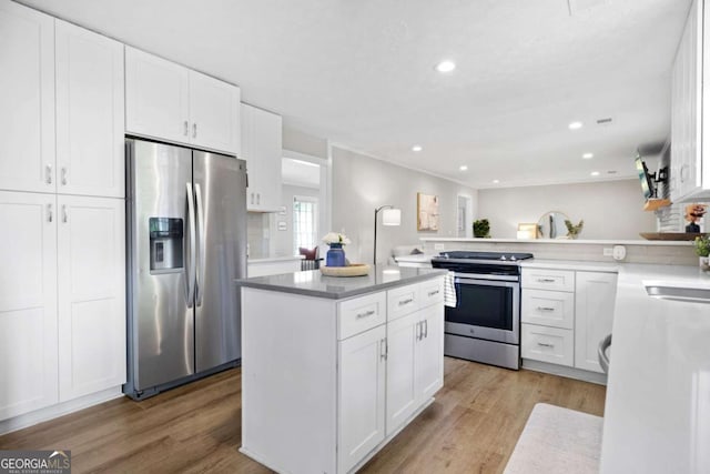 kitchen featuring a kitchen island, stainless steel appliances, white cabinets, and light wood-style floors