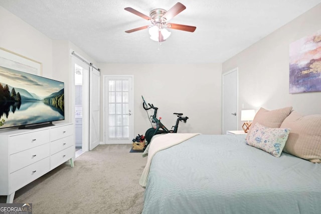 bedroom featuring light colored carpet, a barn door, and a ceiling fan