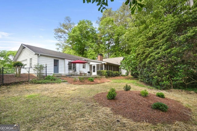 view of front of home featuring fence, a chimney, a sunroom, and a garage