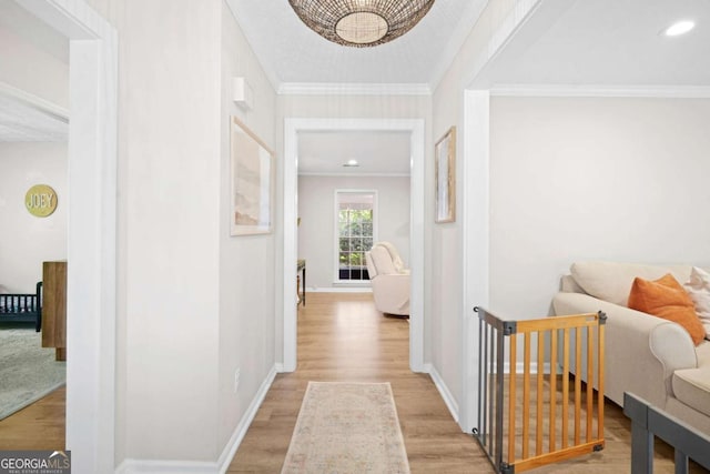 hallway featuring crown molding, baseboards, and light wood-type flooring