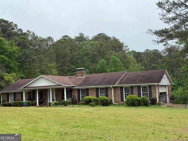 view of front of home featuring a porch, a front lawn, a chimney, and brick siding