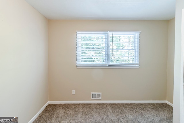 carpeted empty room featuring baseboards and visible vents