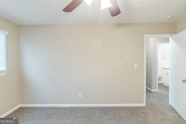 carpeted spare room with ceiling fan and baseboards