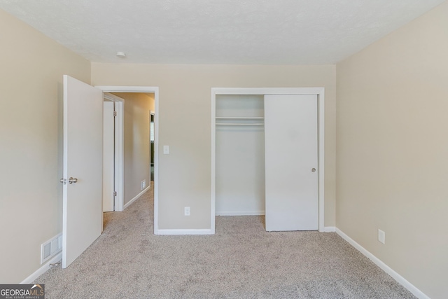 unfurnished bedroom featuring visible vents, carpet, baseboards, and a closet
