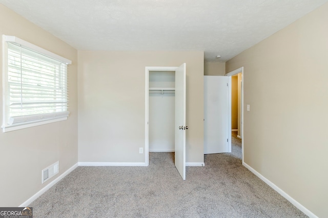 unfurnished bedroom featuring visible vents, baseboards, carpet floors, and a closet