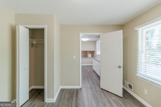 unfurnished bedroom featuring baseboards, a closet, light wood finished floors, and visible vents