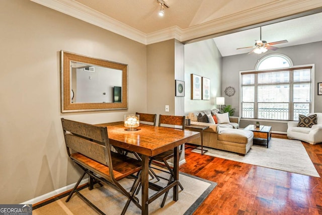dining area with wood finished floors, ornamental molding, vaulted ceiling, a ceiling fan, and baseboards