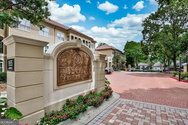 community sign featuring decorative driveway and a residential view