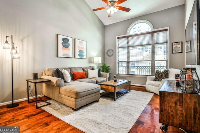 living room featuring a ceiling fan, baseboards, high vaulted ceiling, and wood finished floors