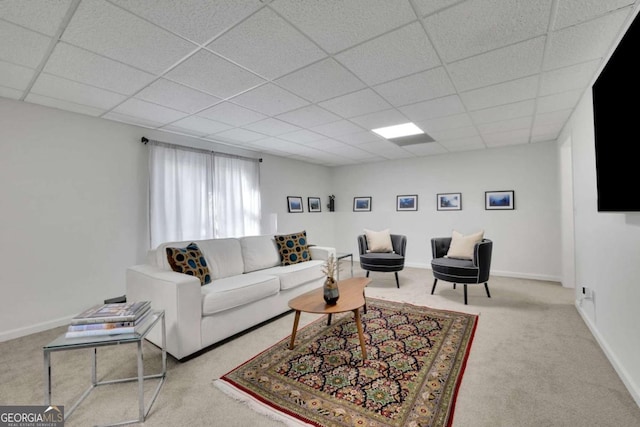 living room featuring a paneled ceiling, carpet, and baseboards