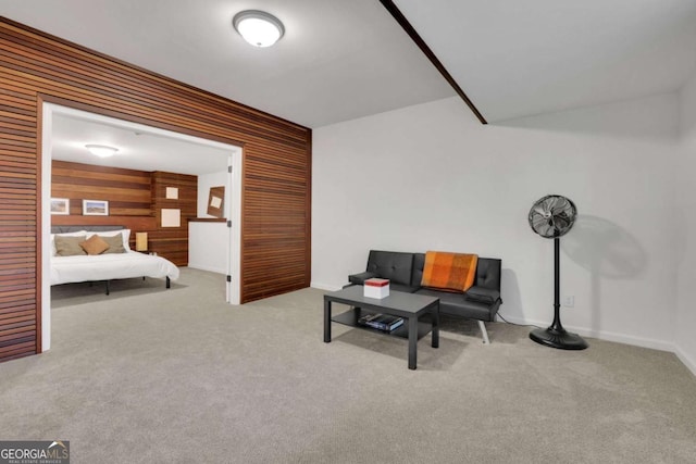 carpeted living room featuring baseboards and wooden walls