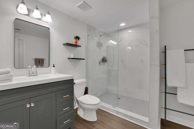 full bathroom featuring toilet, a marble finish shower, visible vents, and wood finished floors