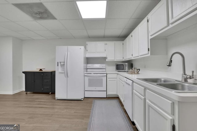 kitchen with white appliances, light wood-style floors, a sink, white cabinetry, and a paneled ceiling