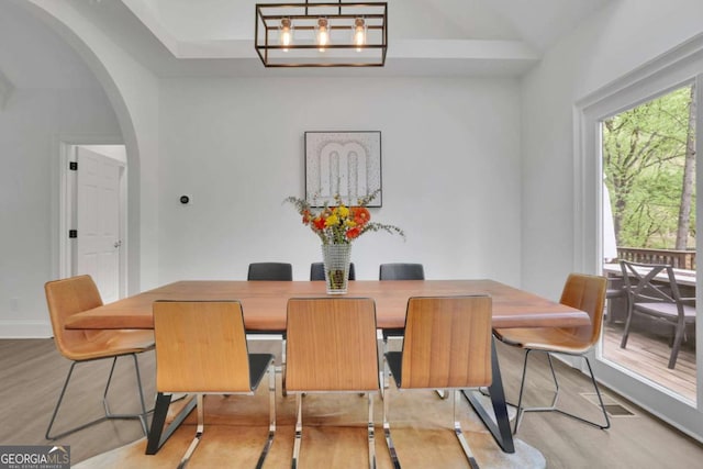 dining room featuring baseboards, arched walkways, and wood finished floors