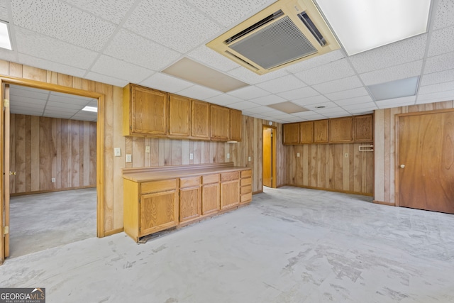 kitchen with wood walls, a paneled ceiling, and concrete floors