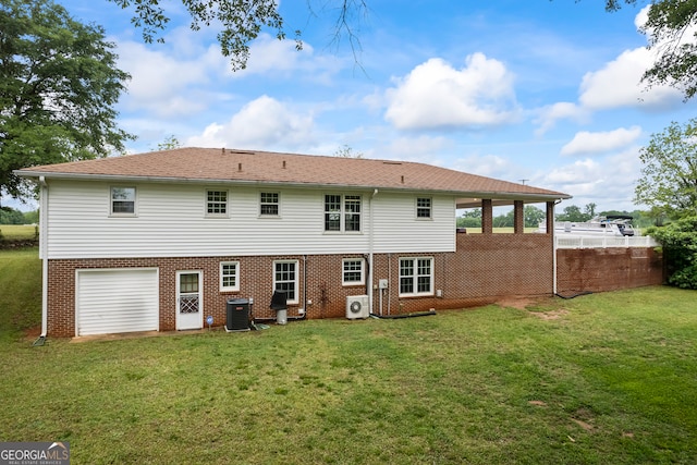 rear view of house with a garage, fence, brick siding, a lawn, and central air condition unit