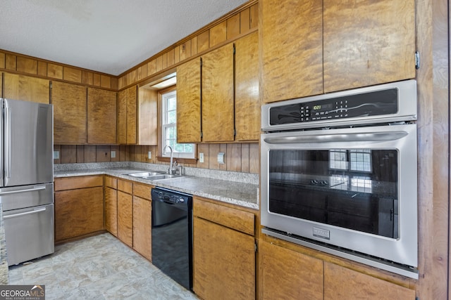 kitchen with light countertops, appliances with stainless steel finishes, brown cabinetry, and a sink