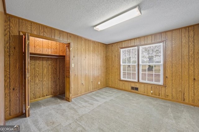 unfurnished bedroom featuring visible vents, a textured ceiling, carpet floors, and a closet