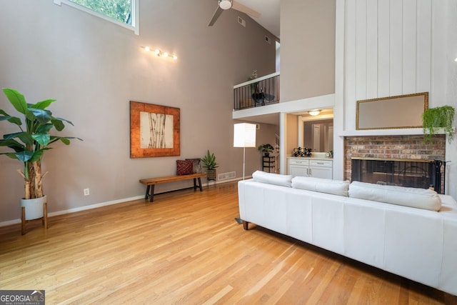 living room featuring plenty of natural light, ceiling fan, light wood-type flooring, and a towering ceiling