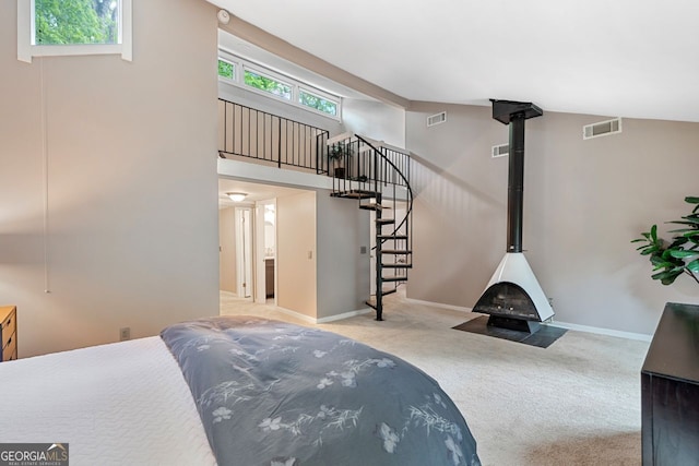 bedroom with visible vents, a wood stove, carpet, and multiple windows