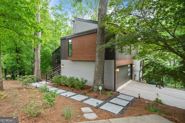 view of home's exterior with concrete driveway, stairway, and a garage