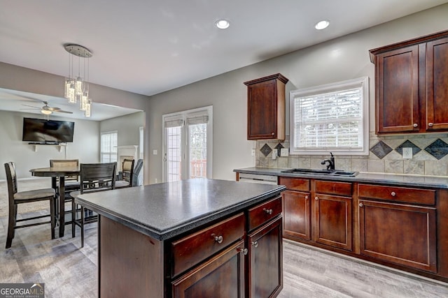 kitchen featuring dark countertops, light wood finished floors, a sink, and a healthy amount of sunlight