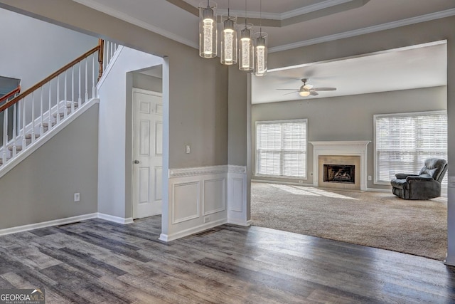 unfurnished living room with stairway, ceiling fan, dark wood-style flooring, and crown molding