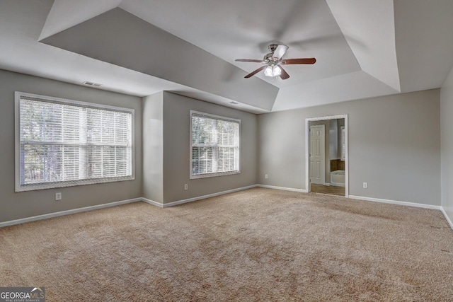 carpeted spare room with baseboards, visible vents, a raised ceiling, and ceiling fan