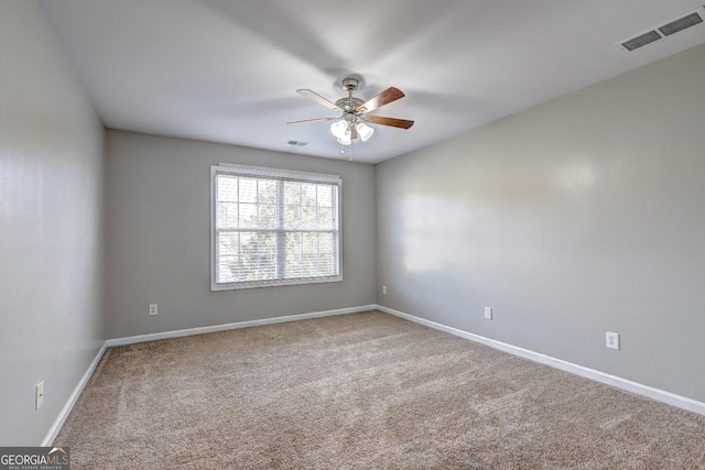 carpeted spare room with visible vents, ceiling fan, and baseboards