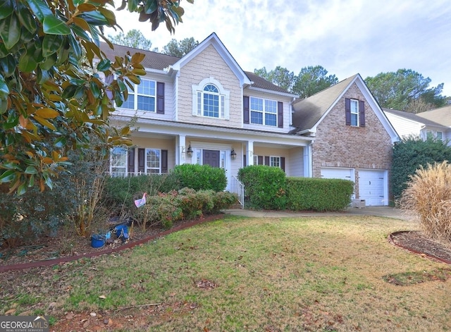 traditional home with driveway, a front yard, brick siding, and a garage